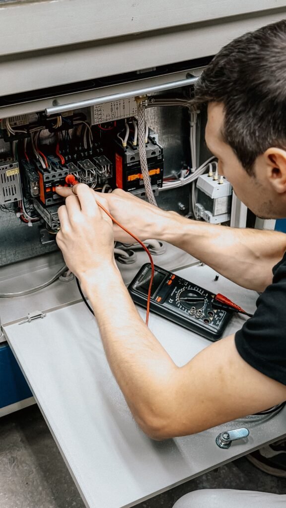 Eletricista utilizando multímetro em painel elétrico aberto